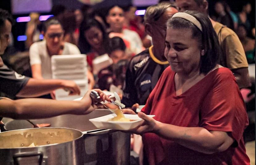 Mulher carente recebendo marmita