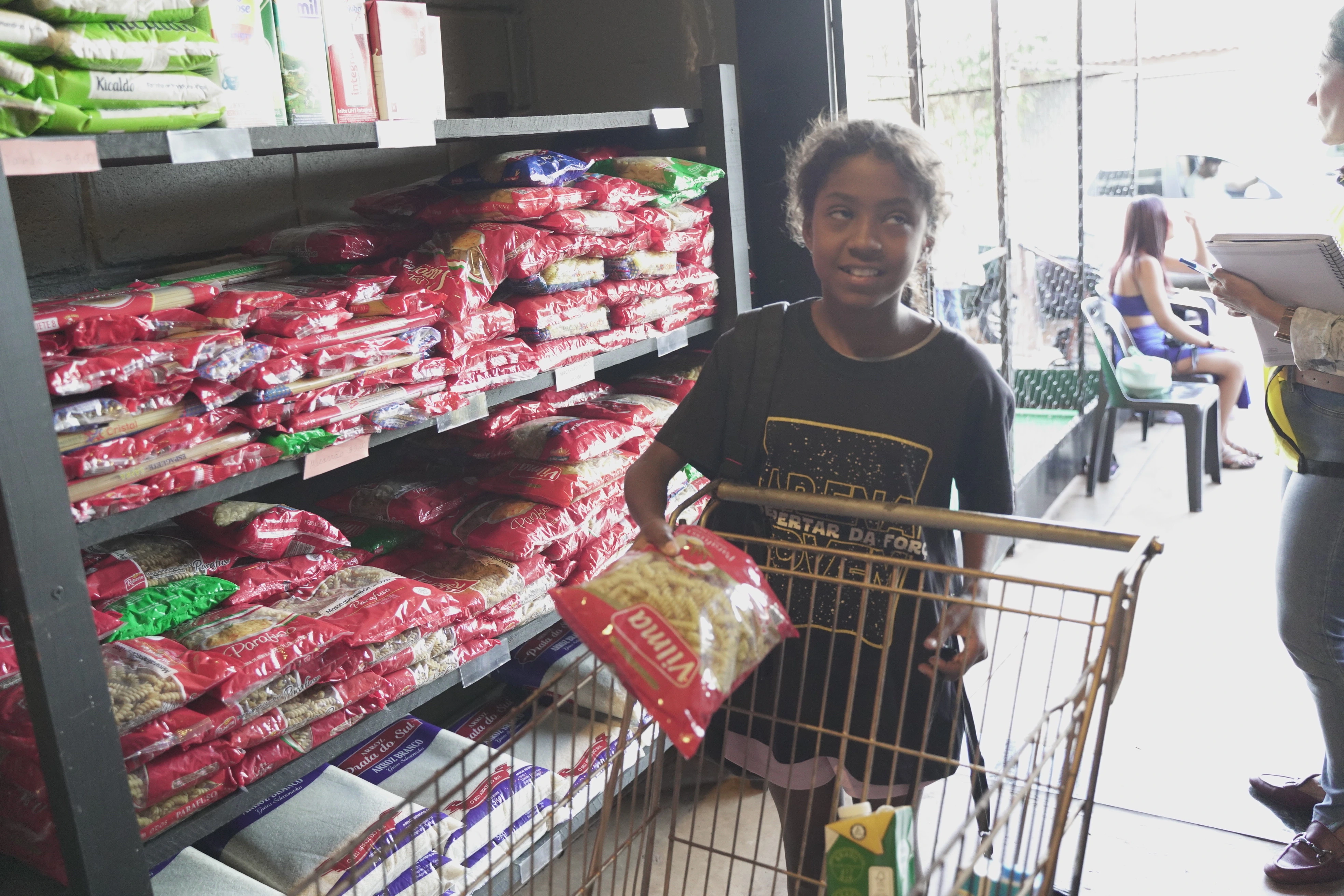 Criança feliz pegando macarrão no mercado solidario